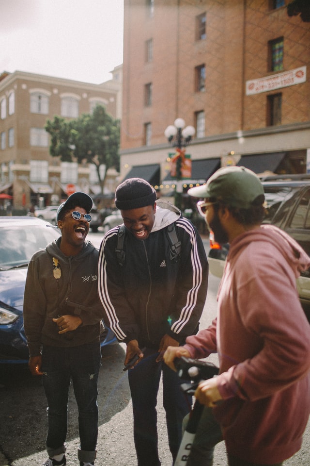 Three guys laughing, One is holding a camera. 