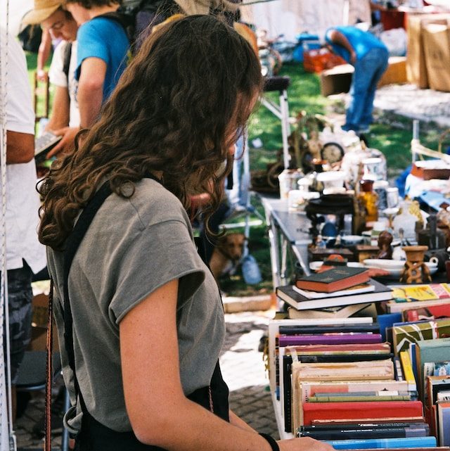 Girl searching through books stacked on a table