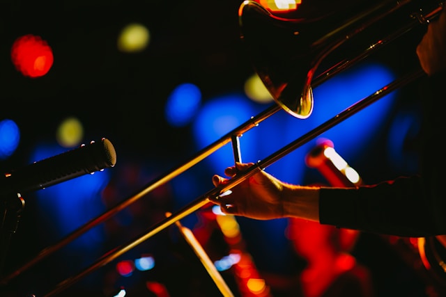 A trombone with a microphone in front of it. A dark out of focus background with colored lights